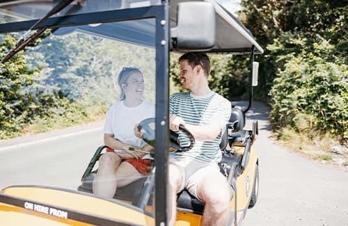 couple travelling on a gold cart around St Mary's - Isles of Scilly