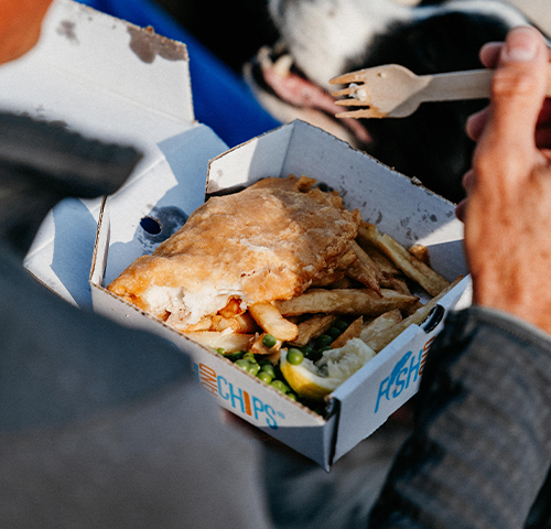 closeup of a Adams Fish and Chips takeaway box with peas, fish and chips in it